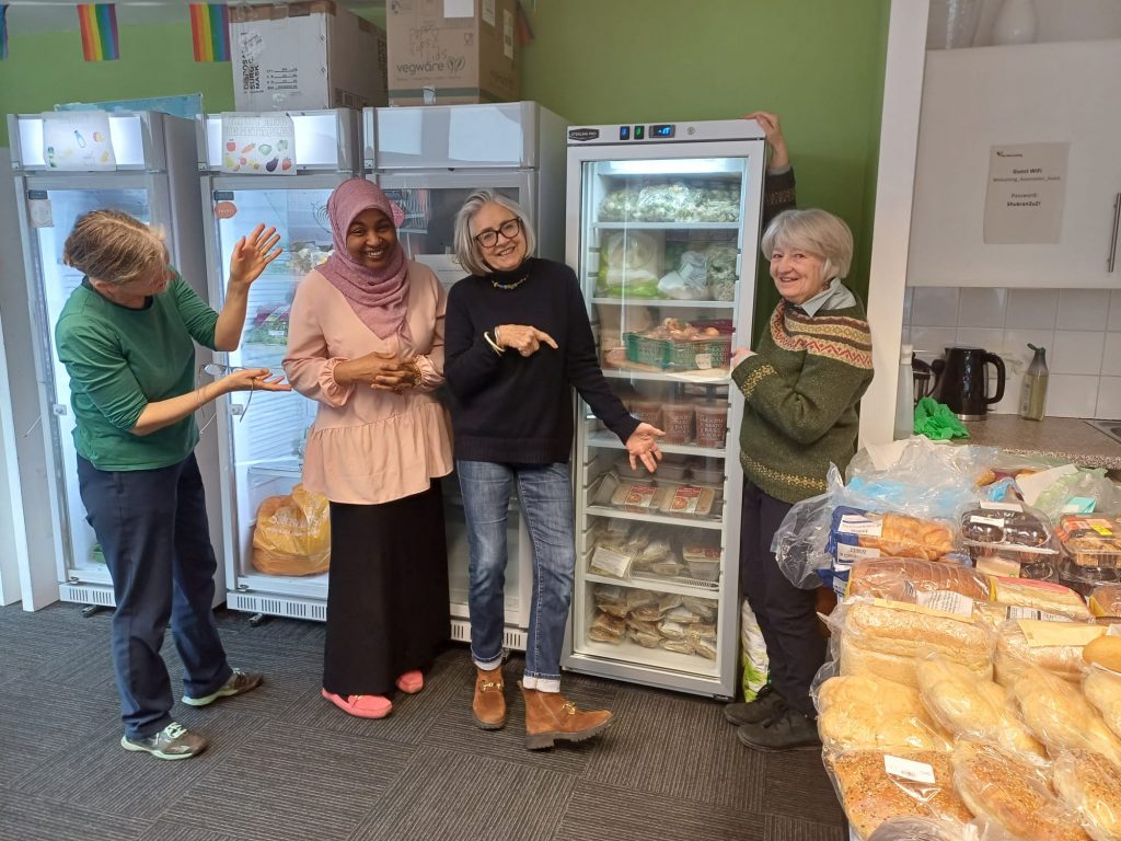 Community Fridge Volunteers standing in front of new freezer full of food for New Scots - refugees, asylum seekers and migrants in Edinburgh.