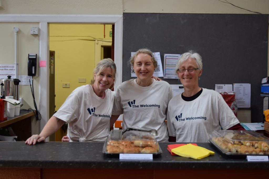 Refugee Festival Scotland Event - a group of three volunteers standing and smiling at the tea station.