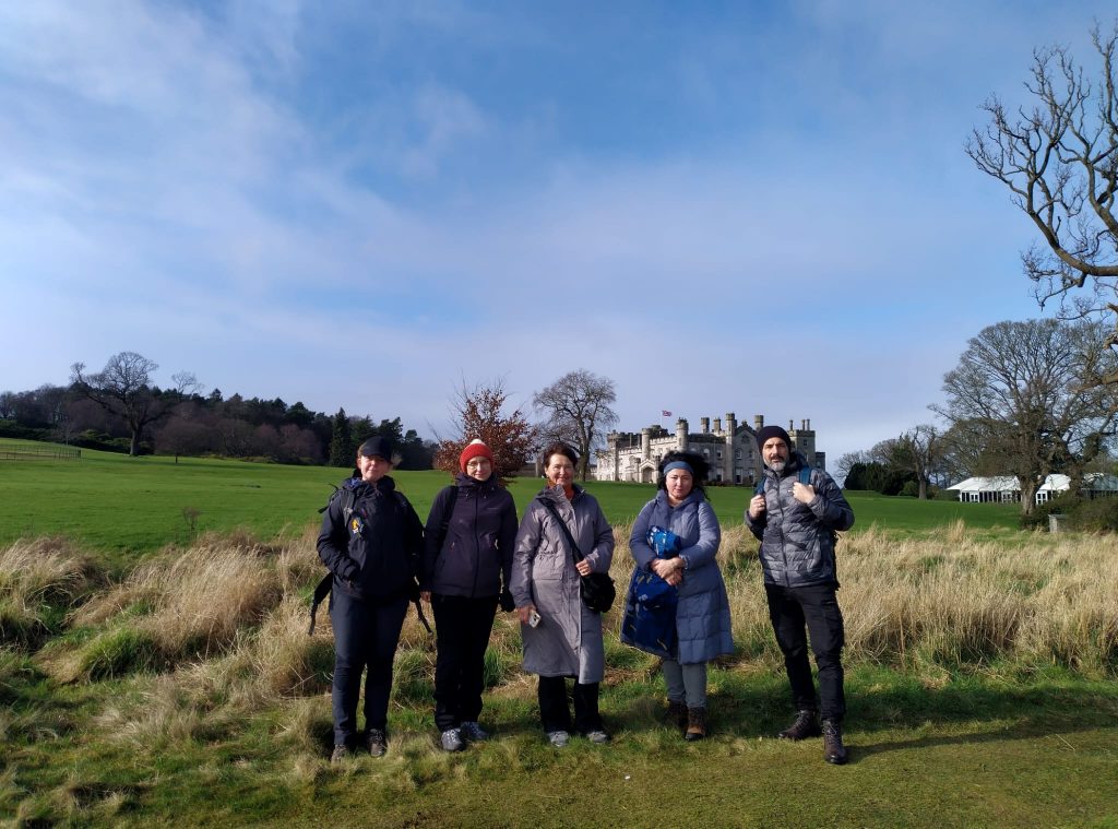 A group of refugees, migrants and volunteers standing in a park in Edinburgh. 