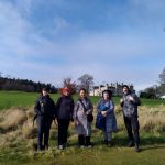 A group of refugees, migrants and volunteers standing in a park in Edinburgh.